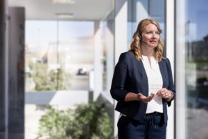 Paper People Planet. Mitarbeiterin mit Headset steht im Bürogebäude.